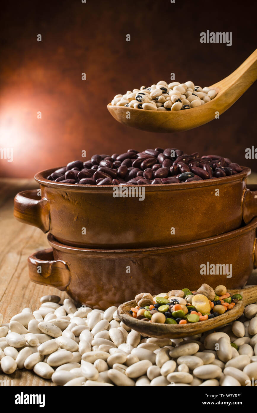 Arten von trockenen Bohnen aus Steingut Topf auf Holz- Hintergrund Stockfoto