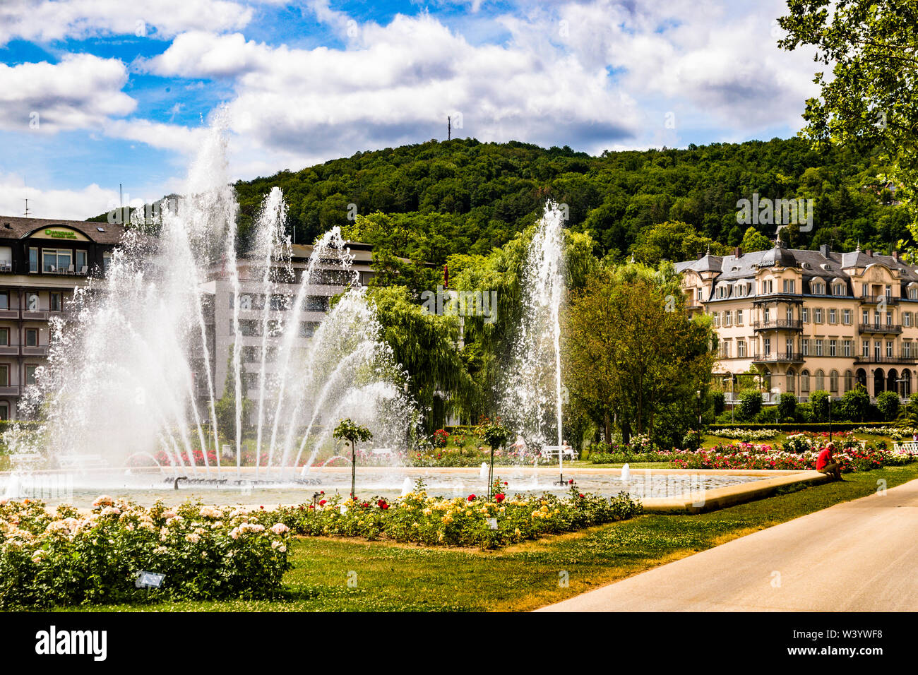 Fächerartige Fontäne im Rosengarten von Bad Kissingen, Deutschland. Der Rosengarten mit Wasserspiel im Zentrum von Bad Kissinger. Die Gärten und Parks sind charakteristisch für das Stadtbild einer Kurstadt. Bad Kissing bietet 110 km Promenaden und Wanderwege. Direkt am Rosengarten fand 1874 die Attentat auf Otto von Bismarck statt, durch die er in ganz Europa berühmt wurde. Stockfoto