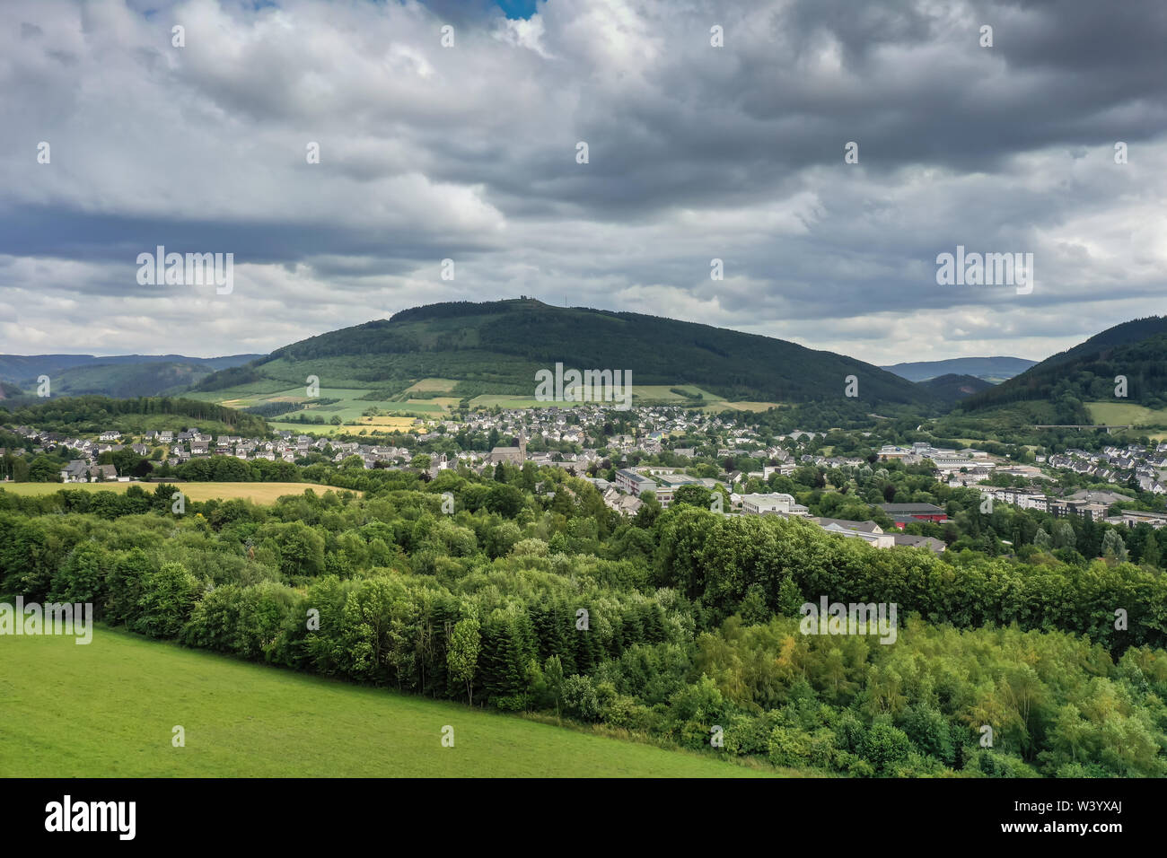 Luftbild von Norden nach Westen auf Olsberg, Nordrhein-Westfalen, Deutschland. Im Juli, die Bäume und die Wiesen sind grün. Bewölkter Himmel über der Stadt. Hohe resol Stockfoto