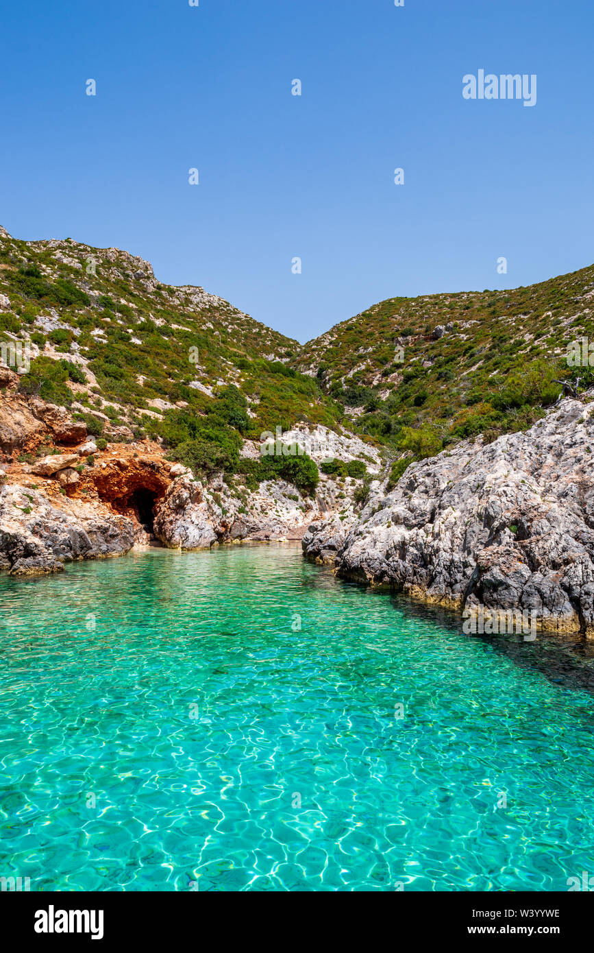 Kleine, paradiesische Bucht von Porto Limnionas mit Blick auf das klare, türkisfarbene Wasser und Fels mit Büschen, Zakynthos, Griechenland Stockfoto