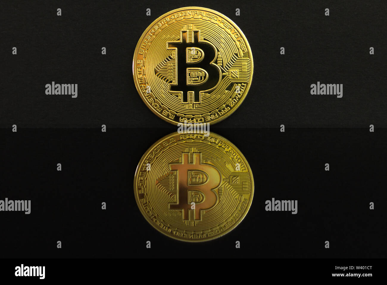 Ein Spiegelbild eines großen goldenen BTC Münze. Die Münze von bitcoin ist auf einem schwarzen Tisch und schwarzen Hintergrund. Golden bitcoin isoliert auf Schwarz Stockfoto