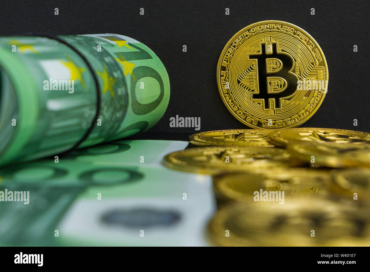 Euro vs Bitcoin cryptocurrency. Es gibt Hundert Euro-Banknoten und großen goldenen btc Münzen auf einem schwarzen Hintergrund. Golden bitcoin über Euro Geld Stockfoto