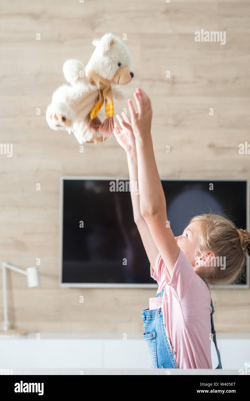 Schöne Mädchen auf dem Sofa umarmen Teddybär. Das Konzept einer glücklichen Kindheit, Spiel in der Familie. Stockfoto