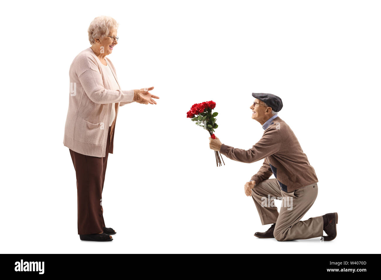 Volle Länge geschossen von einem älteren Mann kniend und mit einem Strauß roter Rosen zu einem älteren Frau auf weißem Hintergrund Stockfoto