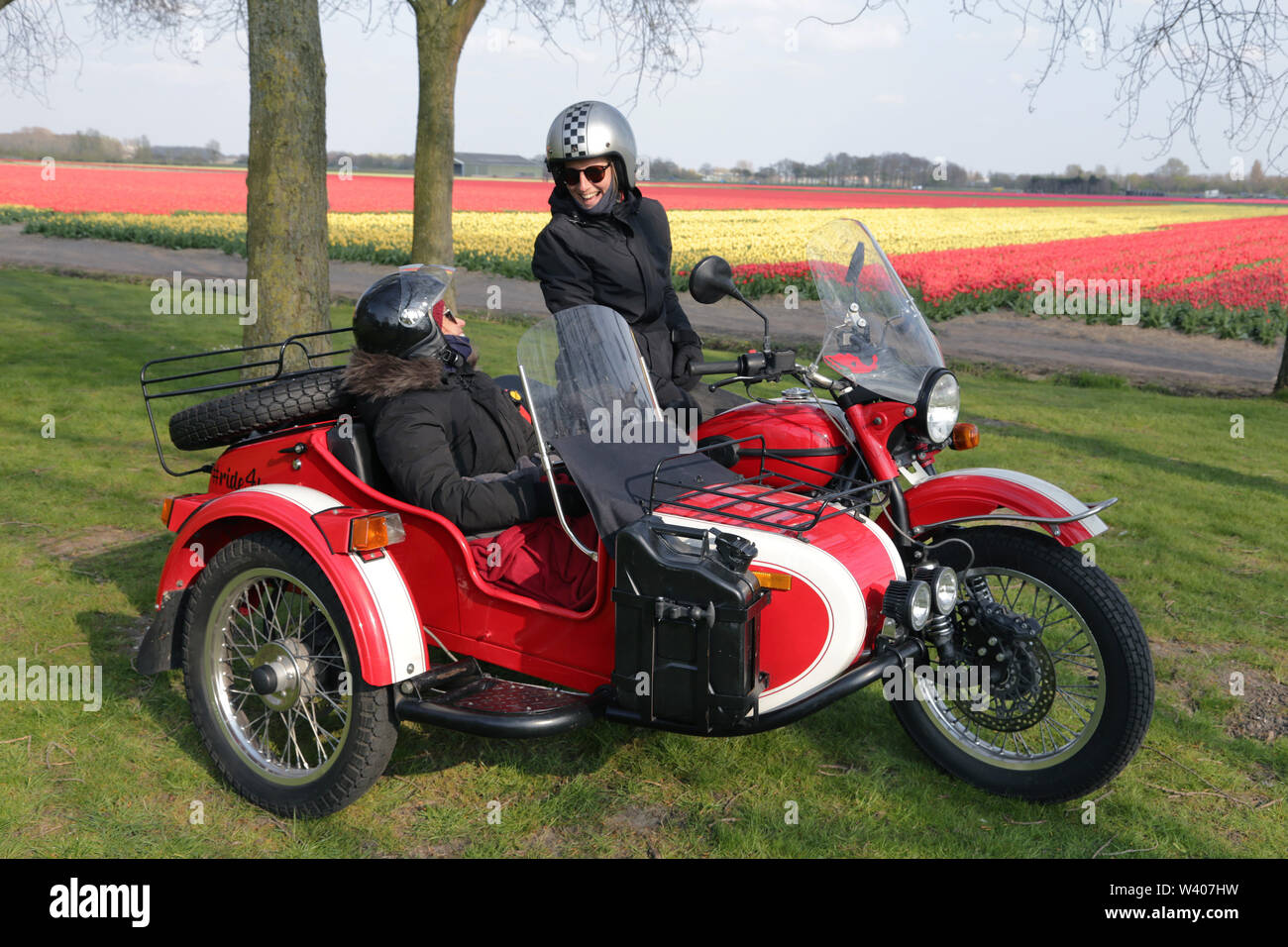 Zwei junge Frauen, die in einem Augenblick in ein rotes Motorrad sitzen Stockfoto