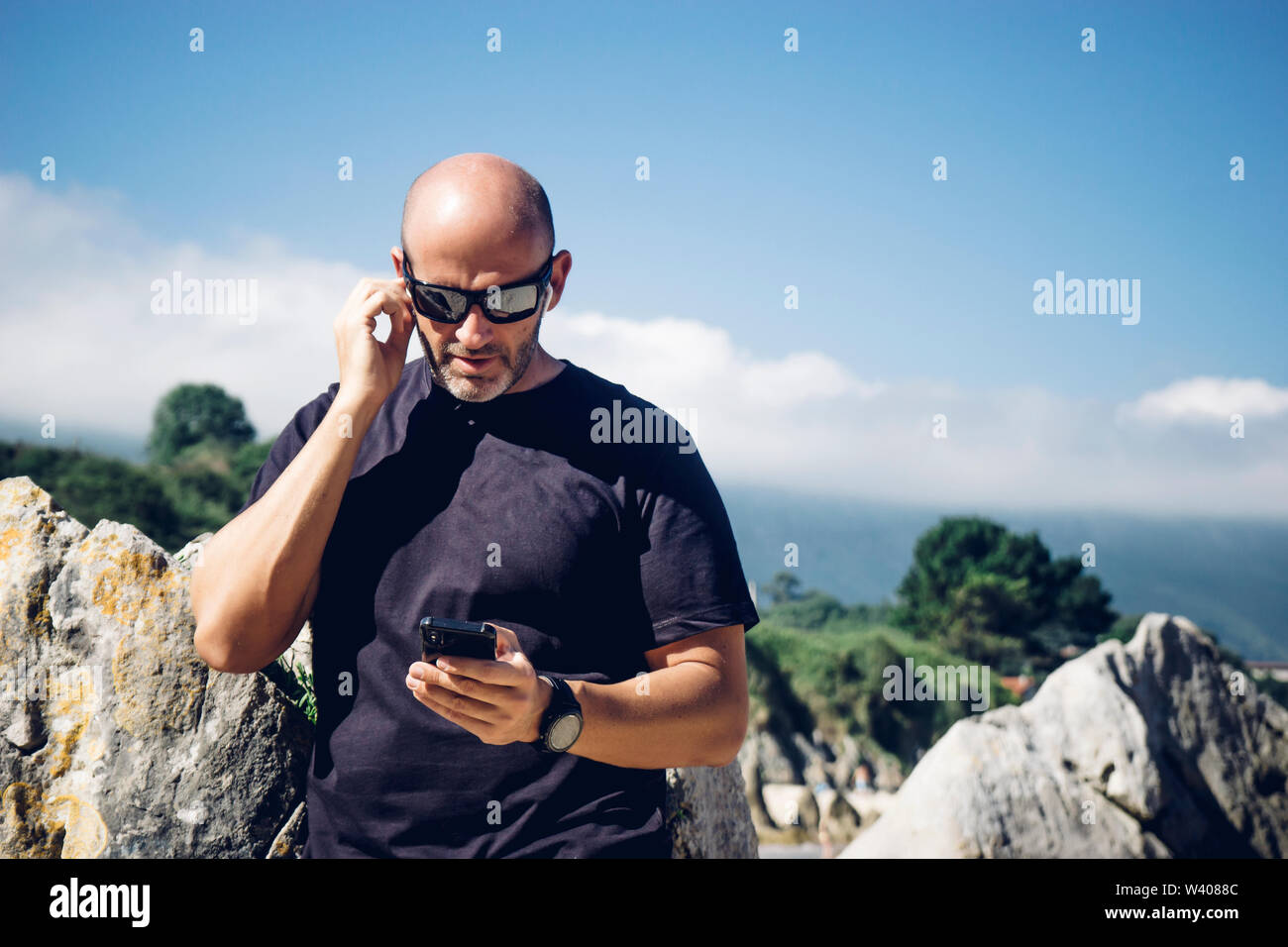 Glatzköpfige Mann mit Wireless Headset und Mobiltelefon. Stockfoto