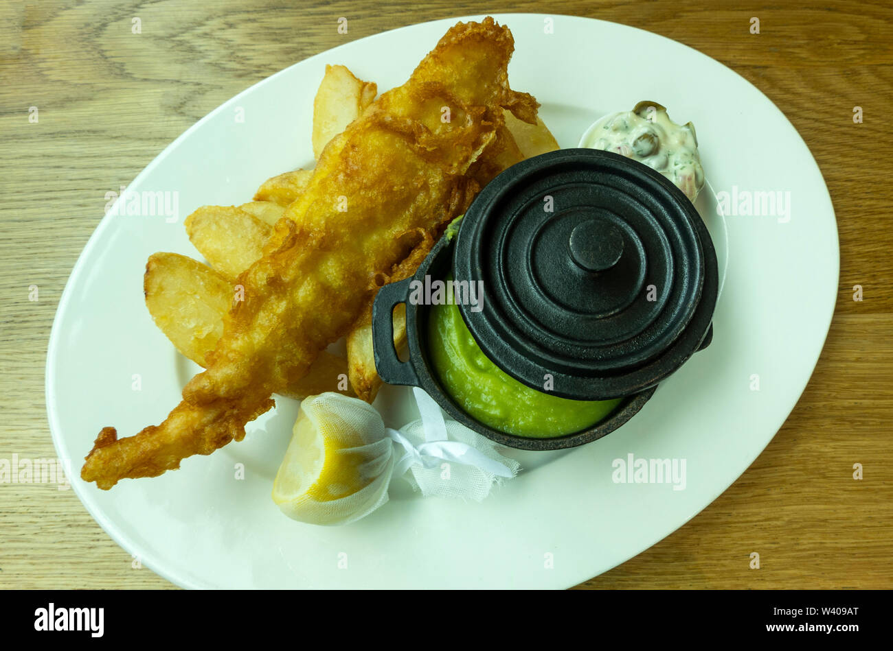 Fish & Chips mit einem Topf mit Erbsenpüree und einen Keil der Zitrone Stockfoto