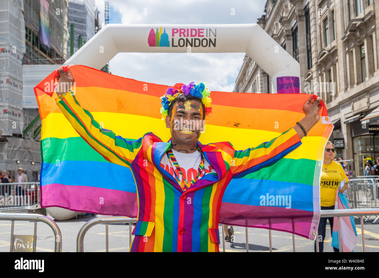 Asiatische Männer in einem Regenbogen Anzug hält einen Regenbogen Flagge im Pride in London Stockfoto