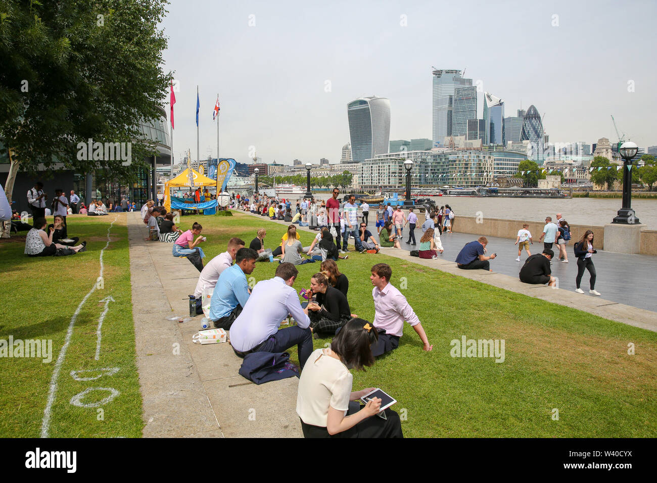 Die in der City arbeiten, und Touristen am Moor in der Nähe der Tower Bridge in einem warmen und sonnigen Tag in London versammelt. Das heiße Wetter in Großbritannien weiter, entsprechend der meteorologische Station, Regen über das Land während der nächsten Tage prognostiziert wird. Stockfoto