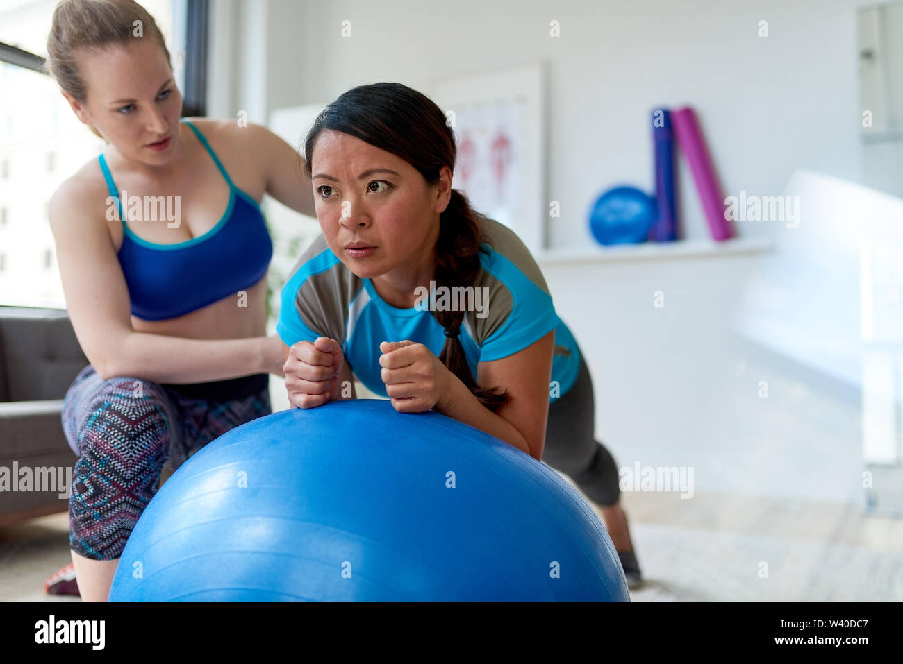 Kaukasische Frau Physiotherapeutin ein Training Session eine Zwischenbilanz nach chinesischen weiblichen Patienten auf einem Gymnastikball Stockfoto