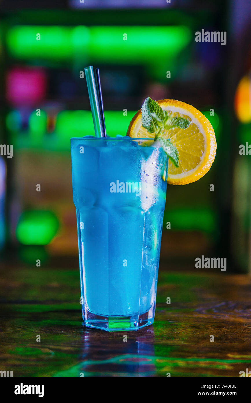 Blue Cocktail in ein hohes Glas Glas mit einer Scheibe Orange. Bunten Cocktail auf der dunklen Rückseite. Cocktail auf einen farbigen Hintergrund in ein hohes Glas. Stockfoto