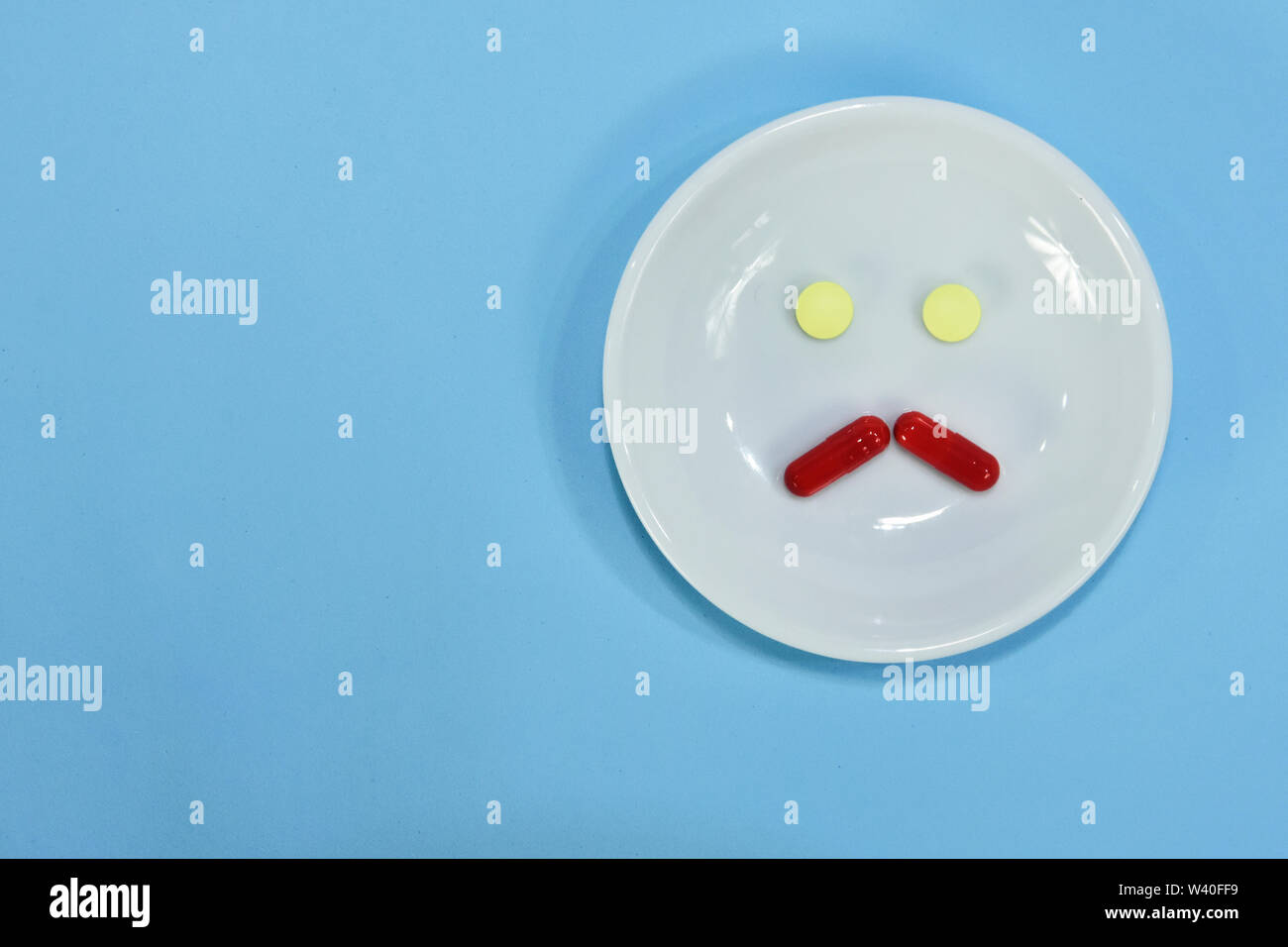 Traurige Gesichtsausdruck aus Medizin. Schmerzmittel Tabletten. farbigen Pillen auf Porzellan Teller. Verschiedene pharmazeutische Pillen. Stockfoto