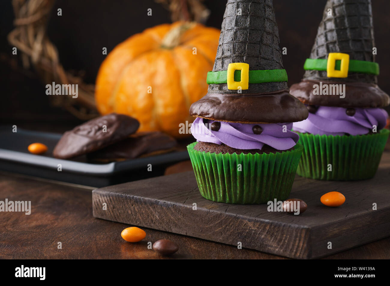 Festliche Halloween Cupcakes mit wafer Hexe Hüte, Süßigkeiten und Schokolade Cookies. Stockfoto