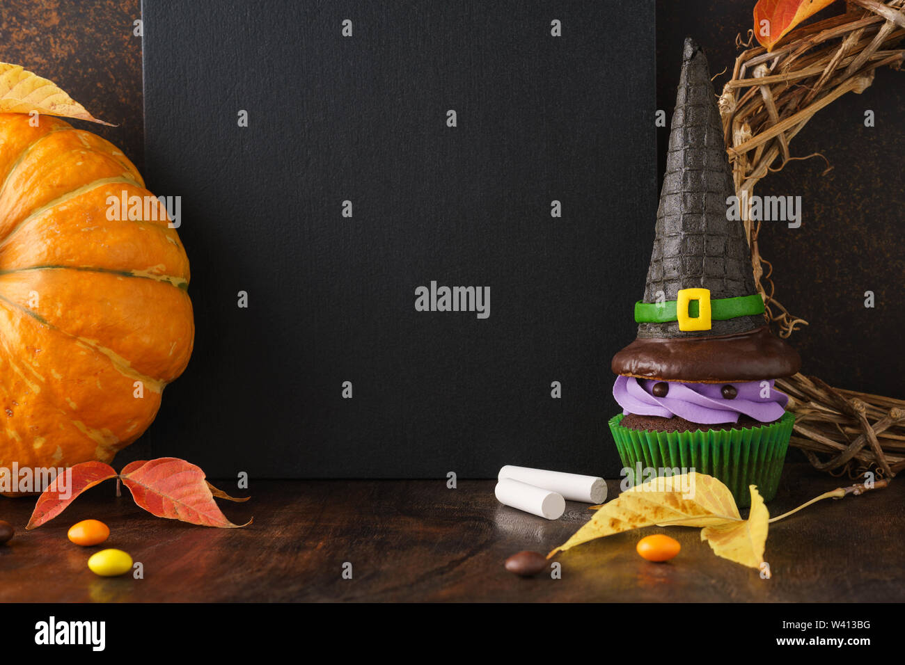 Herbst Jahreszeit festliche Tafel Hintergrund mit Kürbis, Blätter, und Halloween Festlichkeiten - Süßigkeiten und Hexenhut Cupcake. Halloween Verkauf mockup mit Platz Stockfoto