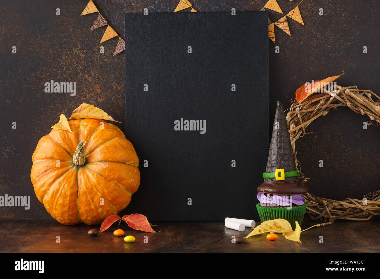 Herbst festliche Tafel Hintergrund mit Kürbis, Blätter, und Halloween Festlichkeiten - Süßigkeiten und Hexenhut Cupcake. Halloween Verkauf mockup mit Copyspace. Stockfoto