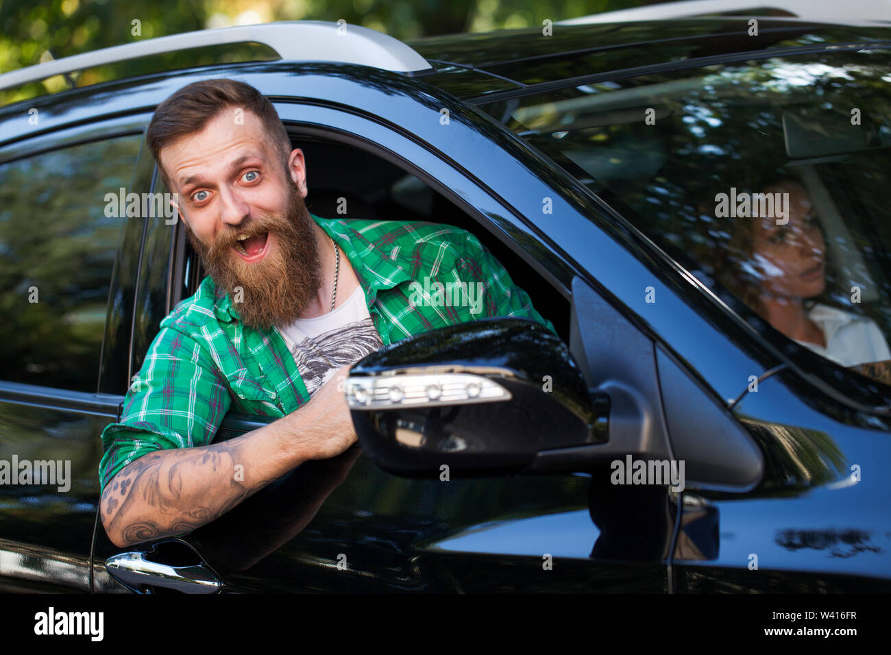 Fröhliche bärtiger Mann im Auto auf der Straße. Stockfoto