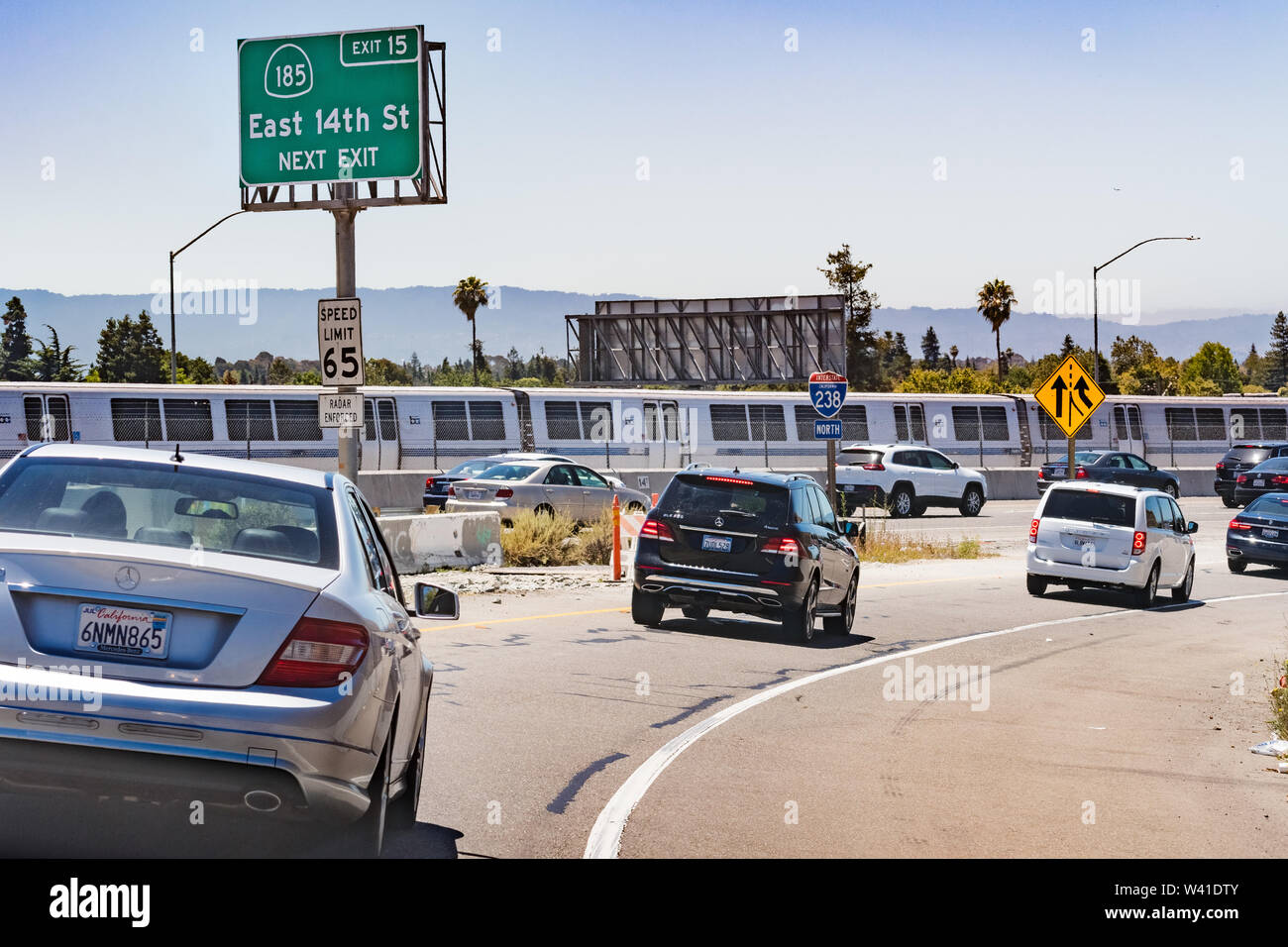 Juli 13, 2019 Hayward/CA/USA - Autobahn Eingang im Osten von der San Francisco Bay Area; BART (Bay Area Rapid Transit)-Zug passiert im Hintergrund Stockfoto
