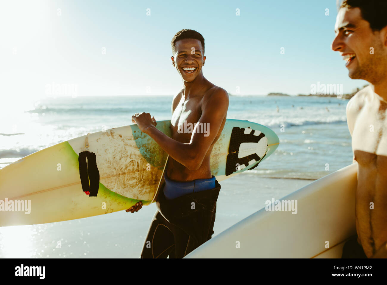 Lächelnde Männer zu Fuß am Strand mit Surfboards. Männliche Freunde auf surfen Ferien am Meer. Stockfoto