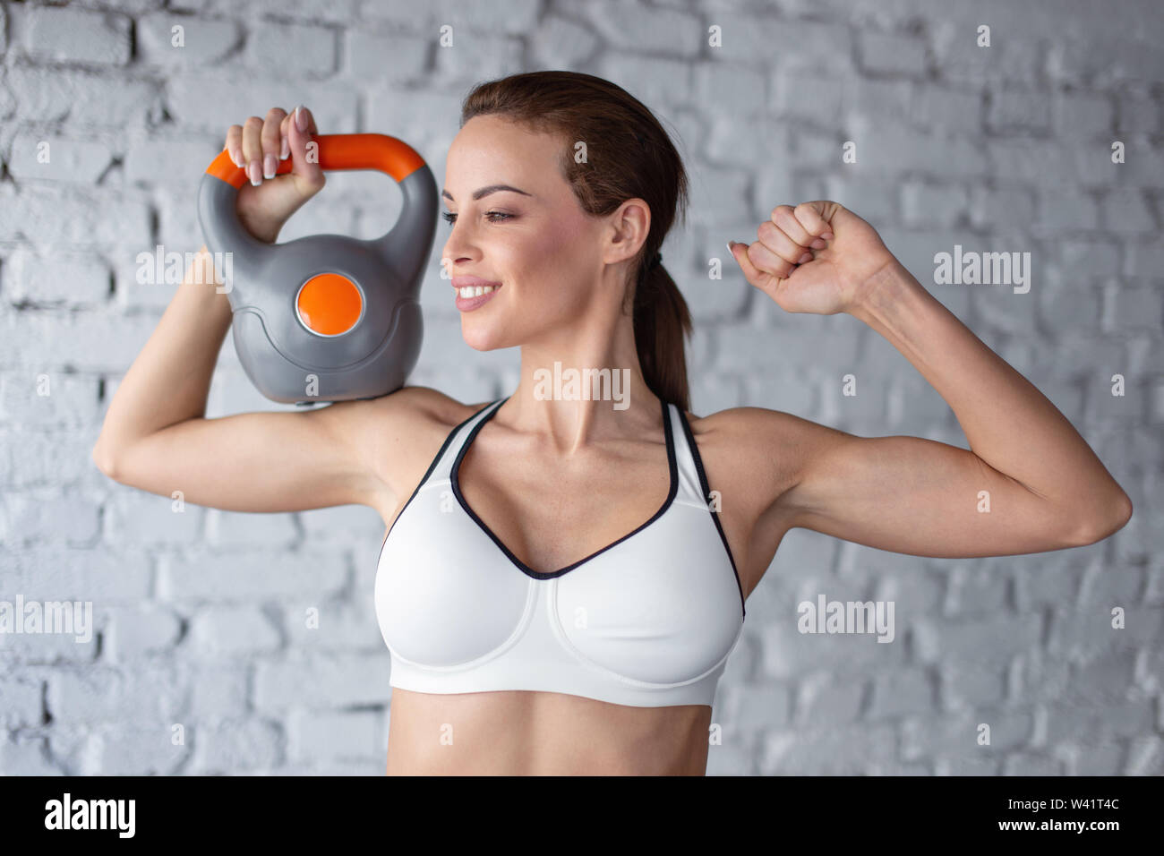 Junge passende Frau in Sportkleidung Holding kettlebell auf der Schulter in der Turnhalle Stockfoto