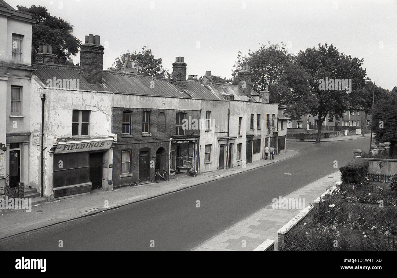 Anfang der 1970er Jahre, historischen, alten viktorianischen Terrasse zeigen, verlassen, Shop, genannt "Fieldings', Wohnraum und Büro für St. Lukes Jugendclubs in Charlton Village, South London, England. Der heruntergekommenen Terrasse scheint Wellpappe stahl Überdachung zu haben. Stockfoto