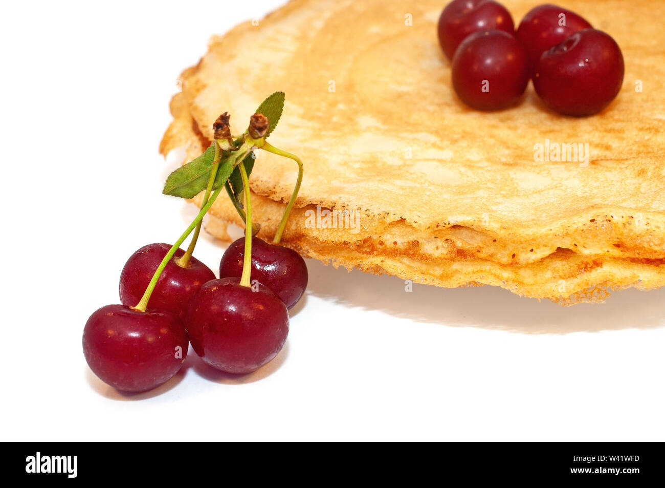 Pfannkuchen zum Frühstück mit Kirschen Beeren isoliert auf weißem Stockfoto