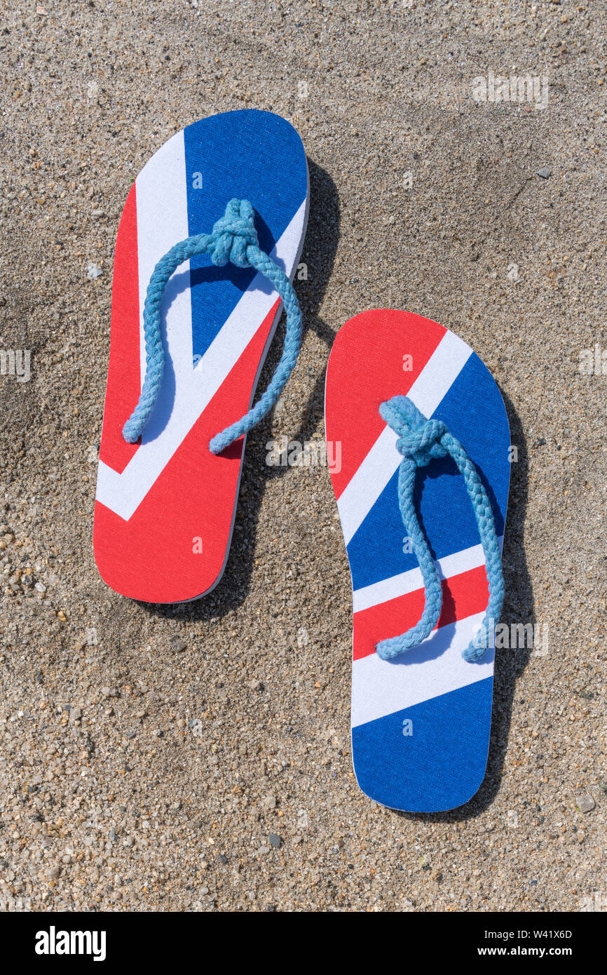 Flipflops mit GB-Flagge / Union Jack am Sandstrand - für 2021 Aufenthalte in Großbritannien, Urlaub zu Hause, Aufenthalt in Cornwall, Badeurlaub, Flip-Flop-Schuhe. Stockfoto