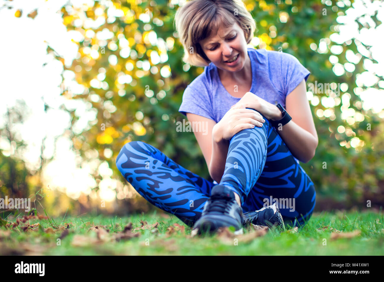 Fitness, Sport, Training und gesunde Lebensweise Konzept - Frau mit verletzten Knie oder Bein im Freien Stockfoto