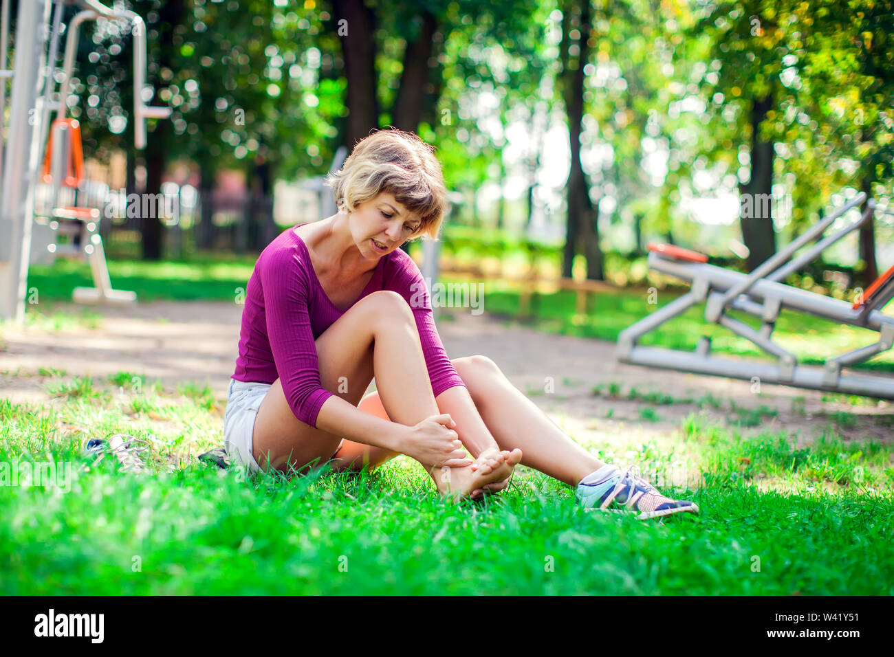 Junge unglückliche Frau Gefühl Schmerz in ihren Fuß beim Sport Training im Park. Sport-, Medizin- und Personen Konzept Stockfoto
