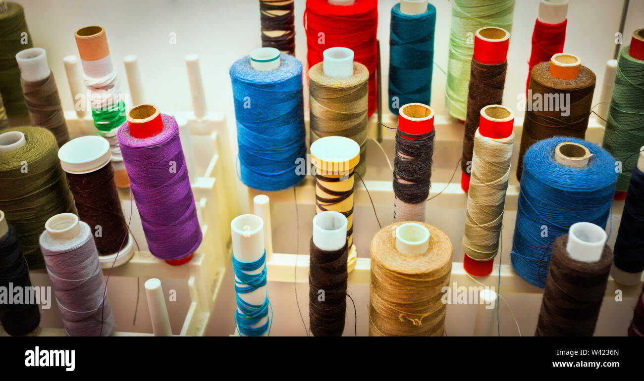 Farbe Spulen in der Nähe auf einem Rack mit verschiedenen Größe Gewinde für Nähmaschine gefüllt Stockfoto