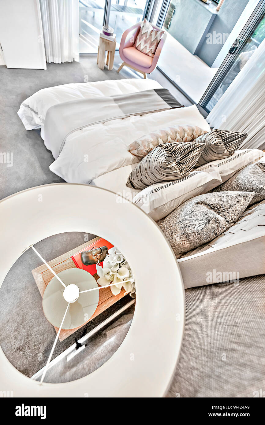 Modernes Schlafzimmer hohen Winkel Blick von oberhalb der Lampe auf dem kleinen Tisch neben dem Bett Kissen und Laken neben Glastüren, bunten Platz auch perfekte l Stockfoto