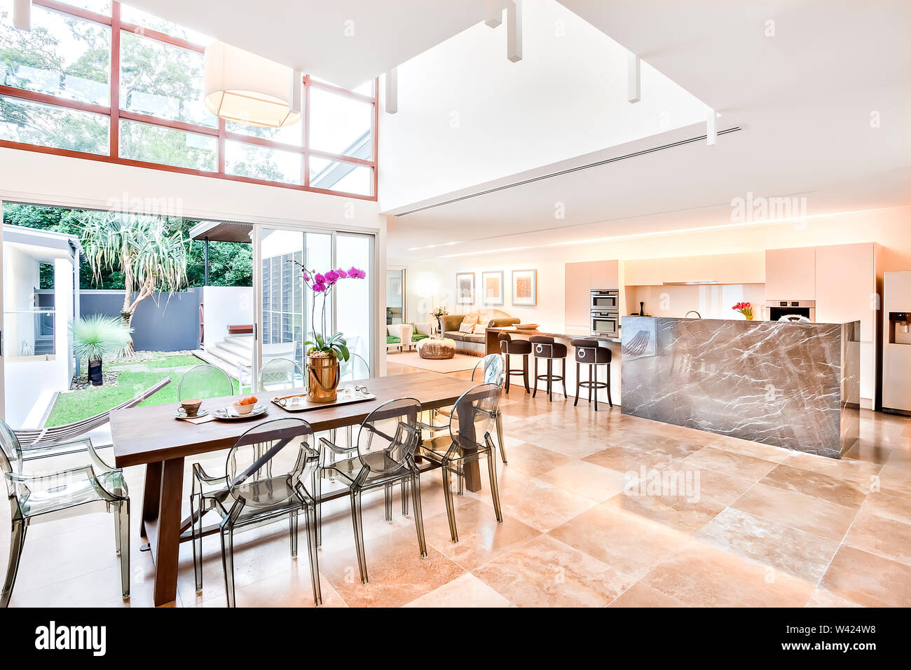 Modernes Haus im Innen- und Außenbereich einschließlich Esszimmer und Küche neben dem Wohnzimmer, der Essbereich oder Terrasse hat einen hölzernen Tisch mit Kunststoff siehe throug Stockfoto