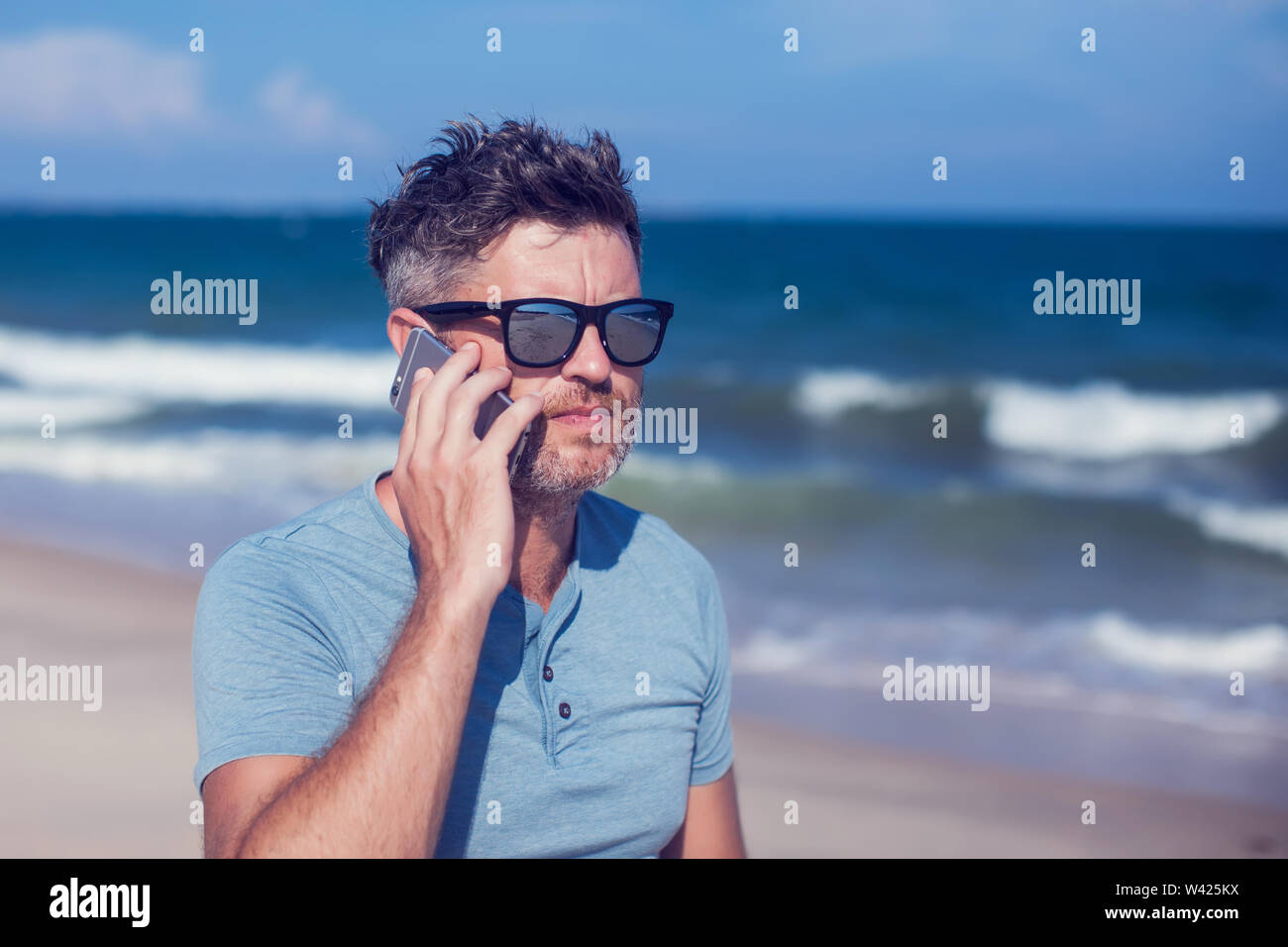 Junger Mann Sie ihr Smartphone am Strand Stockfoto