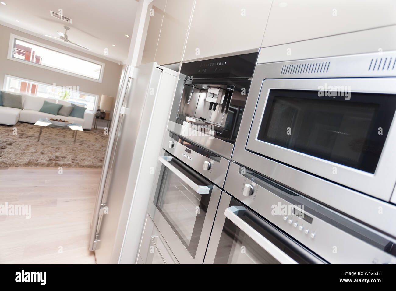 Silber Mikrowelle und Speisekammer Schränke in der Wand in der Küche, den Kühlschrank neben dem Ofen und in der speisekammer ist c Stockfoto
