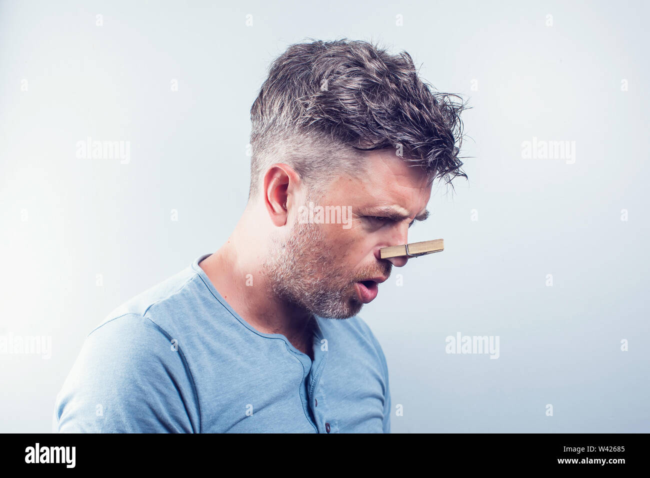 Junger stattlicher Mann mit Wäscheklammer auf der Nase. Allergie Stockfoto
