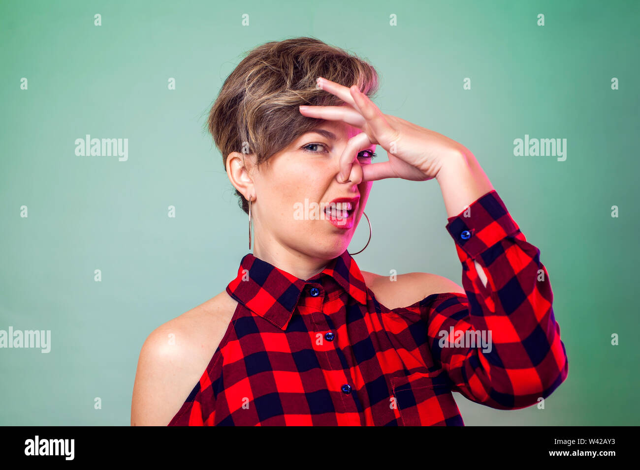 Menschen und Emotionen - ein Porträt der jungen Frau mit kurzen Haaren schließt ihr die Nase von schlechten Geruch Stockfoto