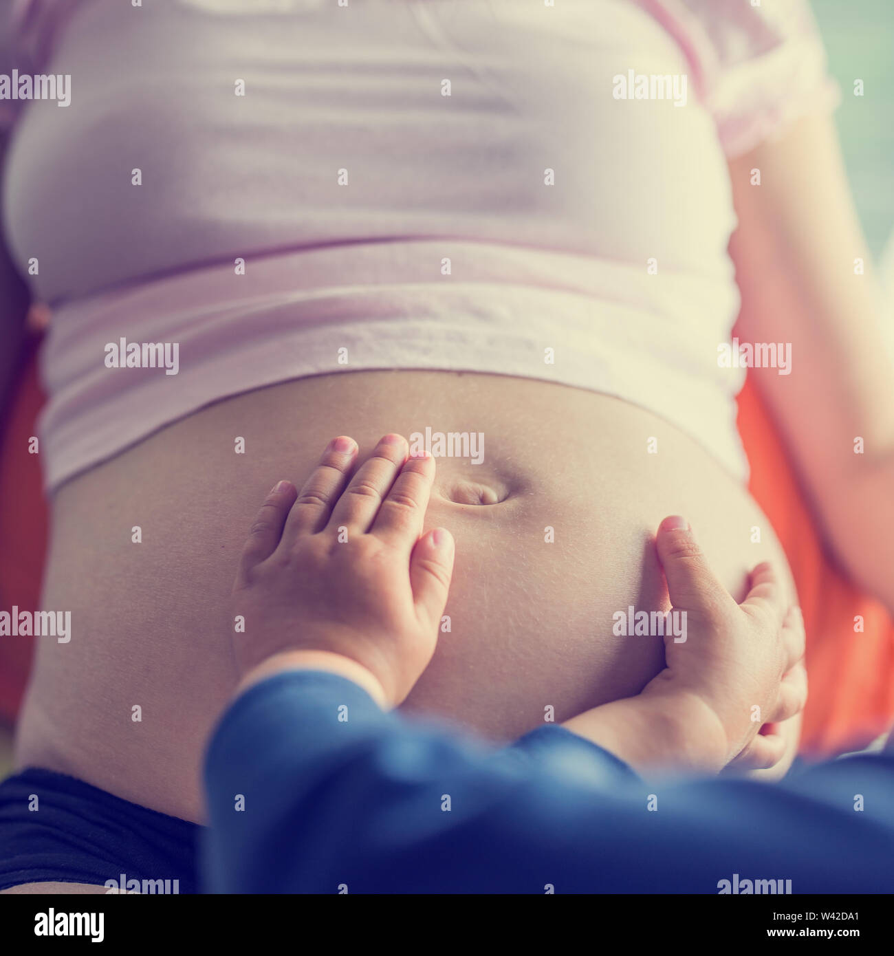 Nahaufnahme von Kleinkind berühren ihre Mammen schwangeren Bauch und Verklebung mit seinem Bruder oder Schwester, getönten retro oder Instagram Wirkung. Stockfoto