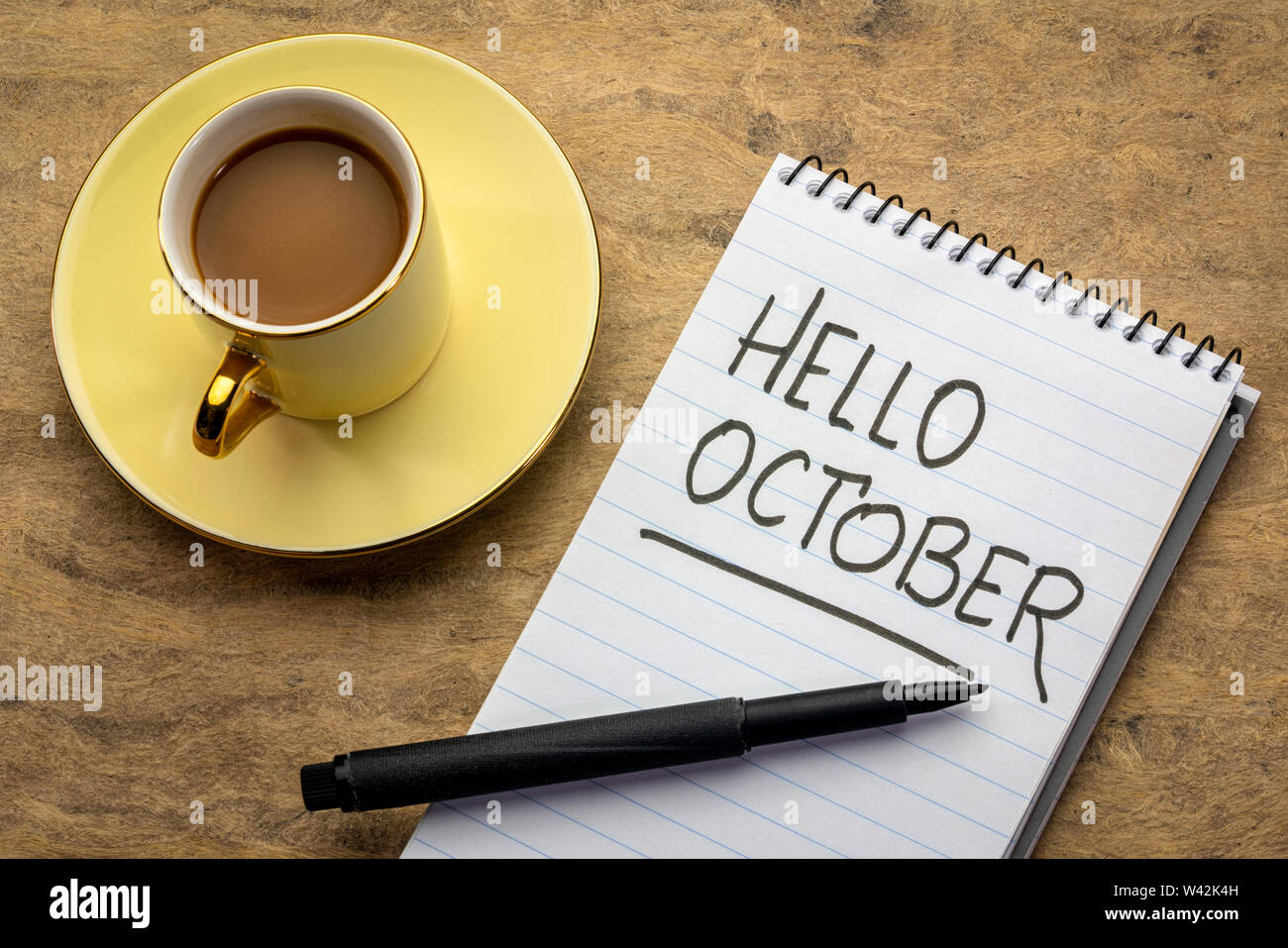 Hallo Oktober - Handschrift in einem Notebook mit einer Tasse Kaffee Stockfoto