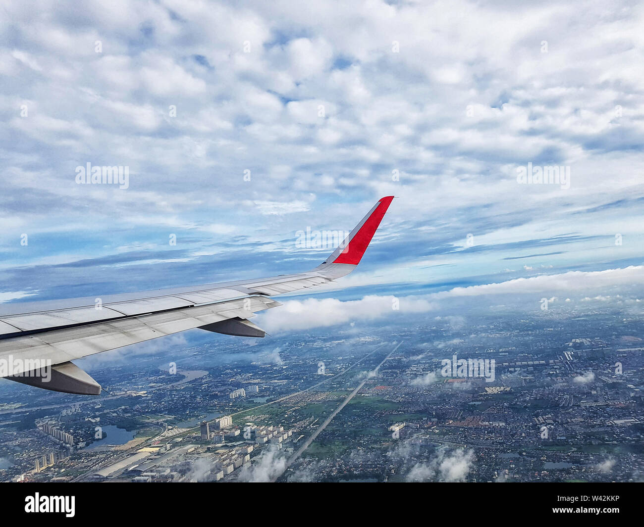 Blick auf die stadt mit Wolken und Himmel, als durch das Fenster eines Flugzeugs gesehen. Reisen und Ferien Konzept Stockfoto