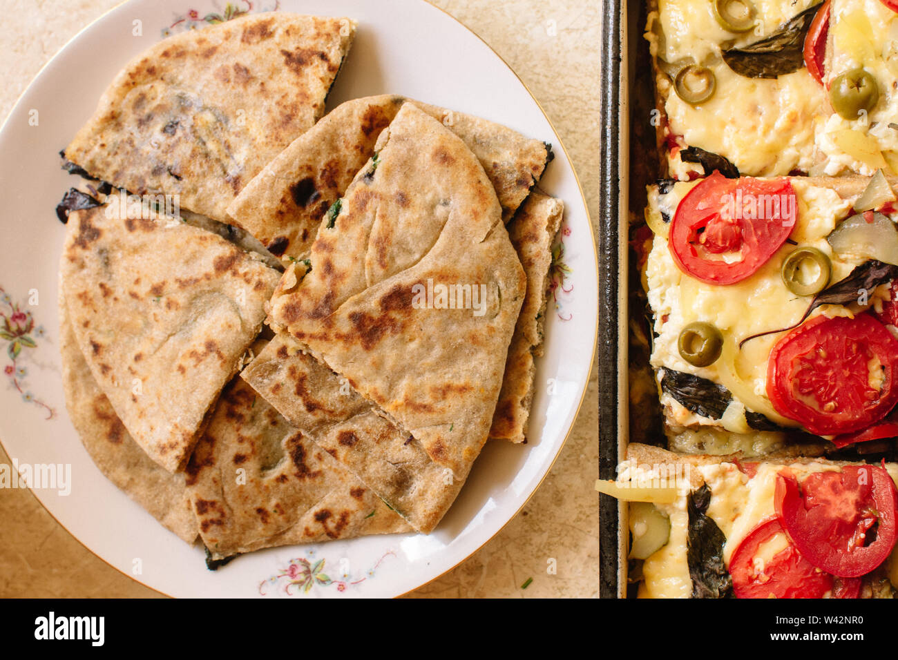 Vegetarische Köstlichkeiten mit Kaffee Pizza mit Tomaten, Mozzarella, Oliven und Naan mit Käse und Grüns Stockfoto