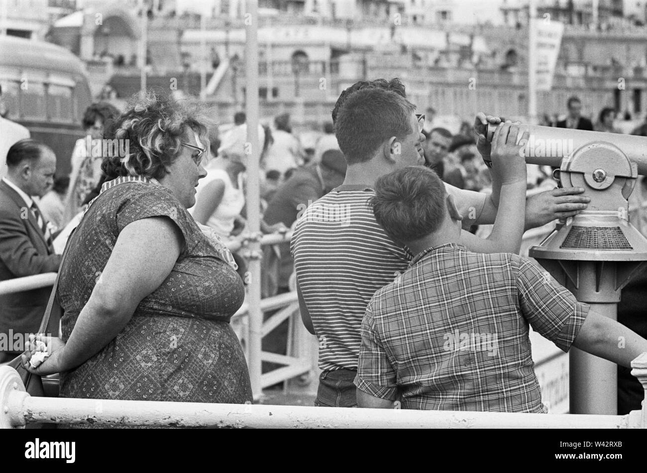Urlaub Szenen am Brighton. Urlauber auf Brighton's Promenade mit Blick auf den Ärmelkanal mit einer der Räte viele Münze touristische Teleskope betrieben. 7. Juli 1963 Stockfoto