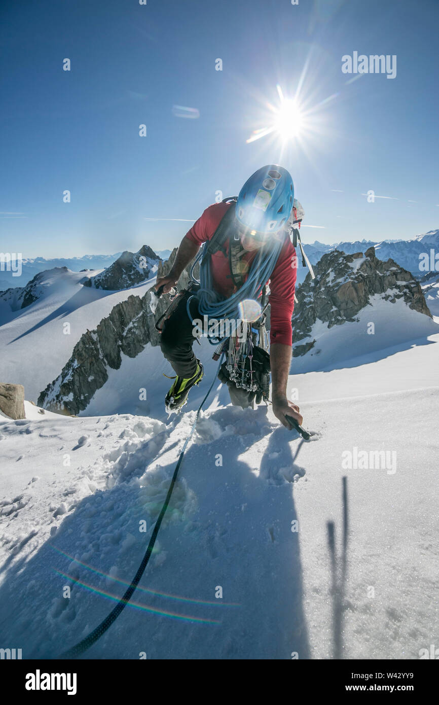 Ein alpinist Tops aus einem steilen Schnee Klettern im Morgenlicht Stockfoto