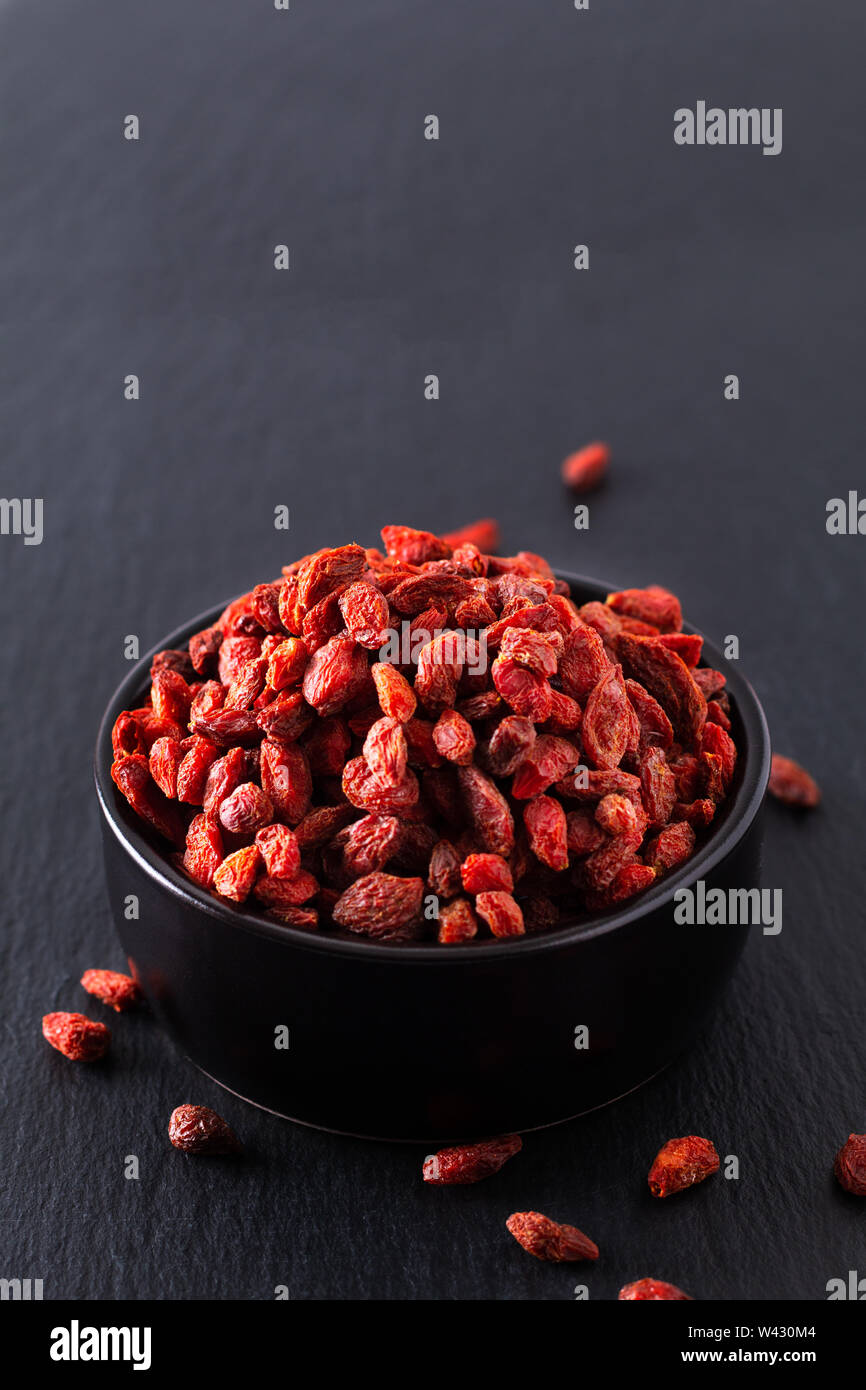 Super Brain Food trocken Goji Beere in Schwarz Keramik Schale auf Schiefer mit Kopie Raum Stockfoto