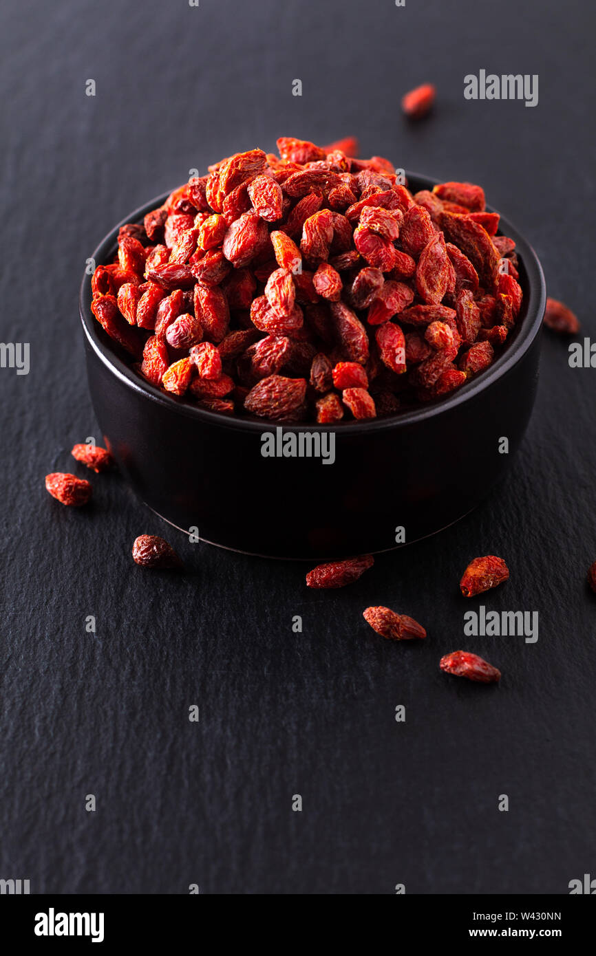 Super Brain Food trocken Goji Beere in Schwarz Keramik Schale auf Schiefer mit Kopie Raum Stockfoto