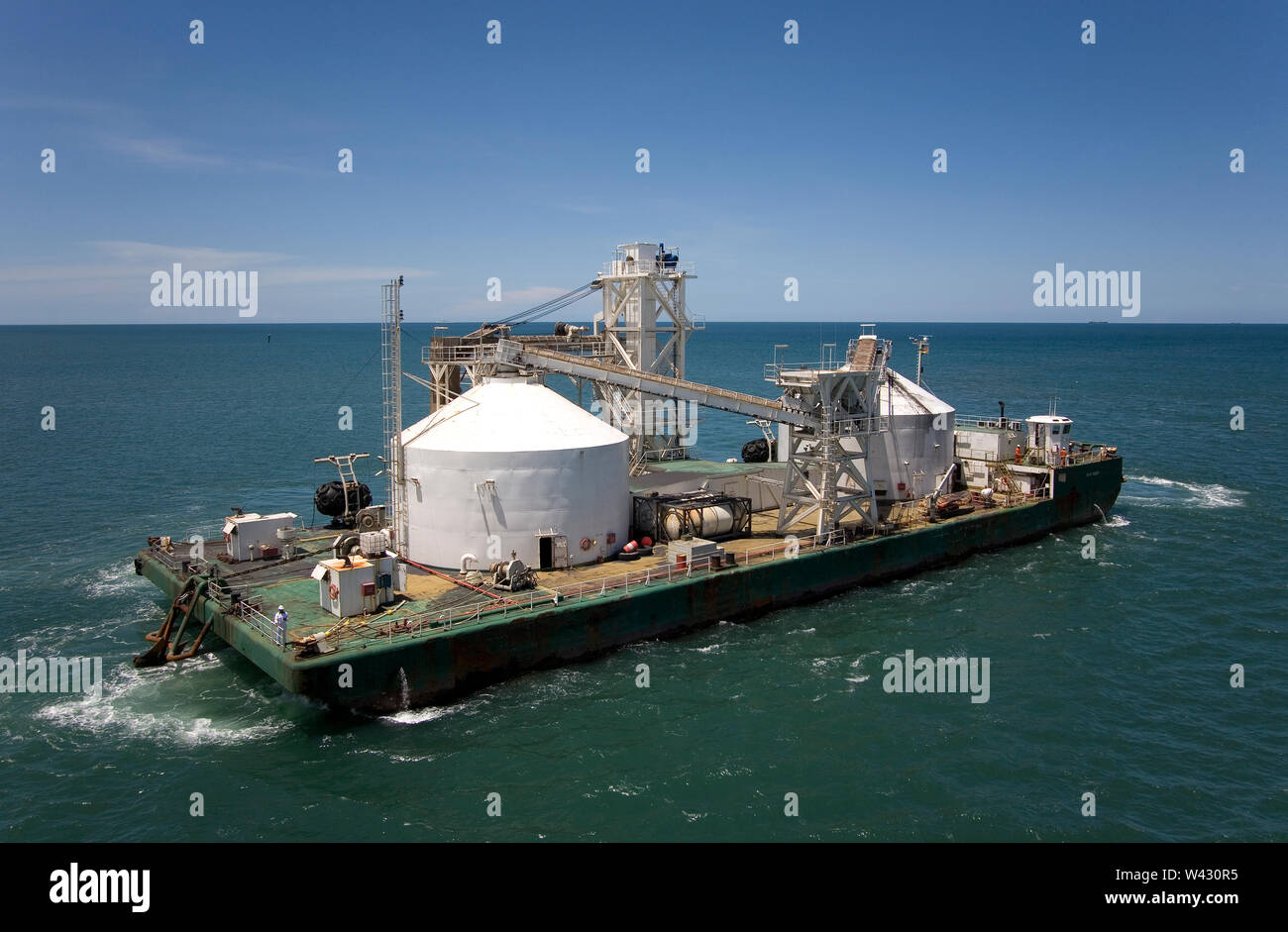 Bergbau, Verwaltung und Transport von Titanmineralsanden. Barge Ankunft am Steg, um mit Mineral zu laden, bevor Sie zu OGV am Horizont Stockfoto