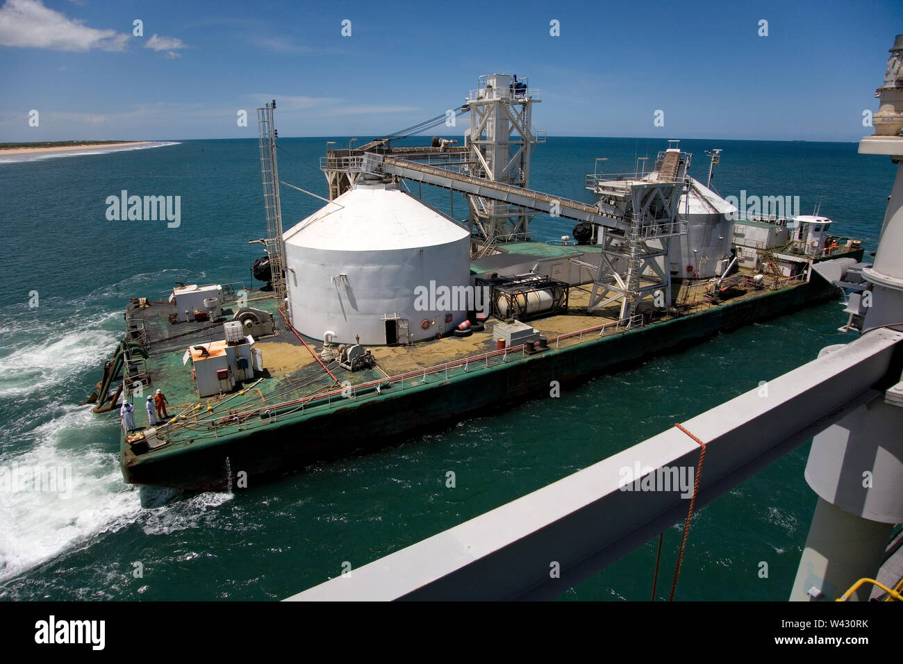 Bergbau, Verwaltung und Transport von Titanmineralsanden. Barge Ankunft am Steg, um mit Mineral zu laden, bevor Sie zu OGV am Horizont Stockfoto