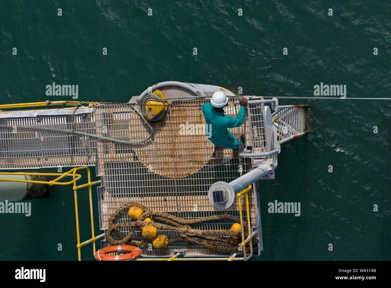 Bergbau, Verwaltung und Transport von Titanmineralsanden. Hafenanlage mit Schiffsarbeiter auf schwimmenden Steg lösen Seil, so geladen Lastkahn segeln kann. Stockfoto