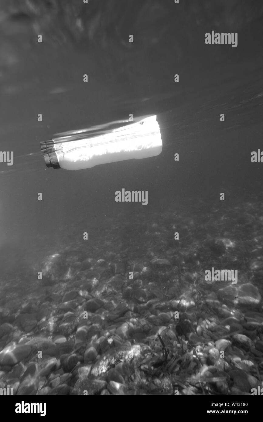 Plastikflasche schwimmen im Meer, Foto unter Wasser mit dem Meeresboden Stockfoto