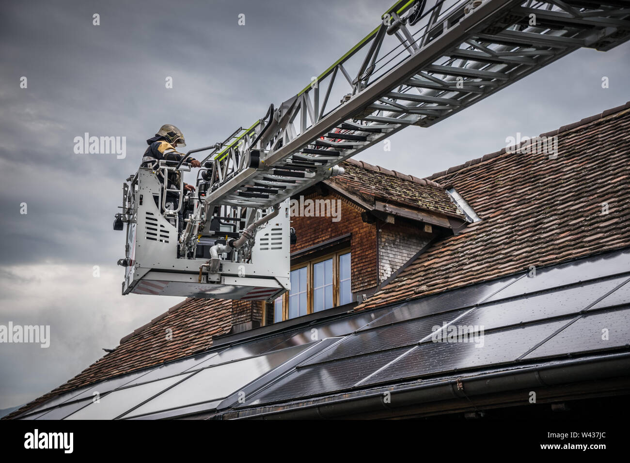 Drehbar Leiter mit Korb über ein Dach mit Gebäude integrierte Photovoltaik Stockfoto