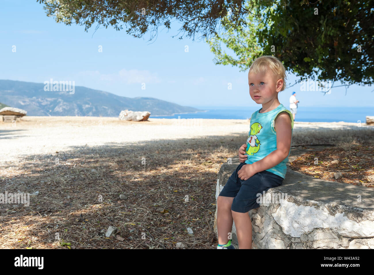 Zwei Jahre alten Sohn auf einem Felsen in der Nähe von Agrilion Monasetery in der Nähe von Sami, Kefalonia, Ionische Inseln, Griechenland, Europa sitzen Stockfoto