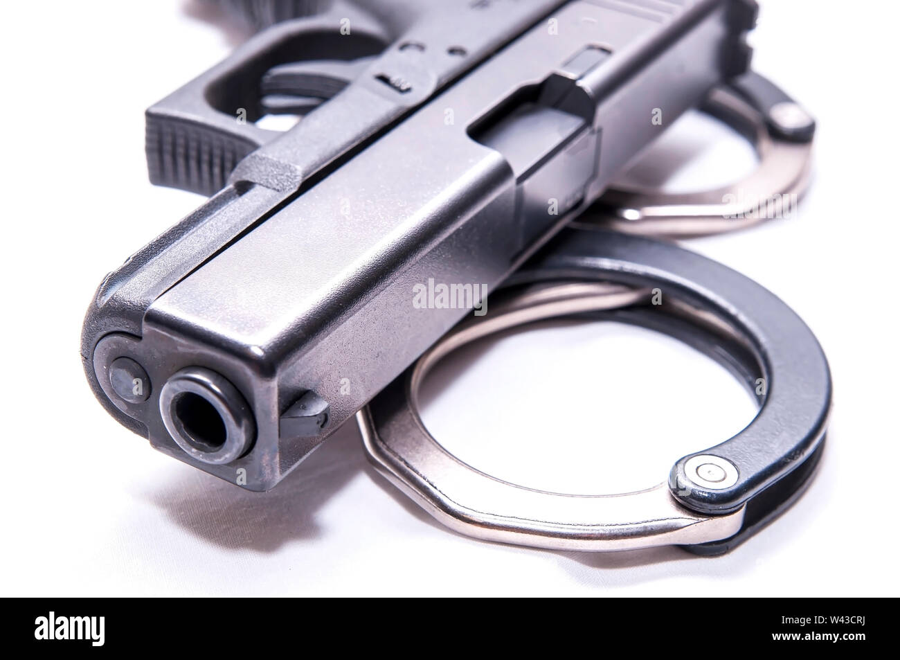 Ein schwarzes 9-mm-Pistole auf einen Satz von Schwarz und Silber Handschellen auf weißem Hintergrund Stockfoto